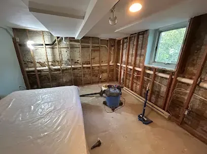 A room opened to the studs with plastic sheeting and a wet vacuum during drying