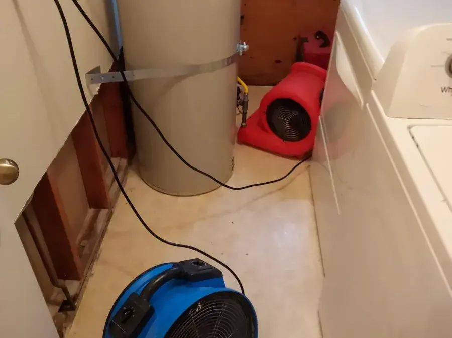 An air mover drying a laundry nook with the wall opened behind the washer