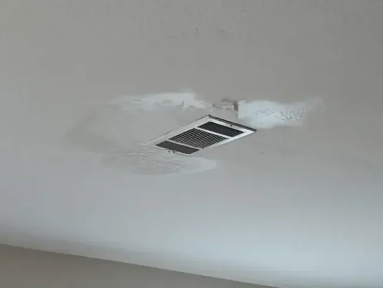 A water-stained ceiling below an attic air handler