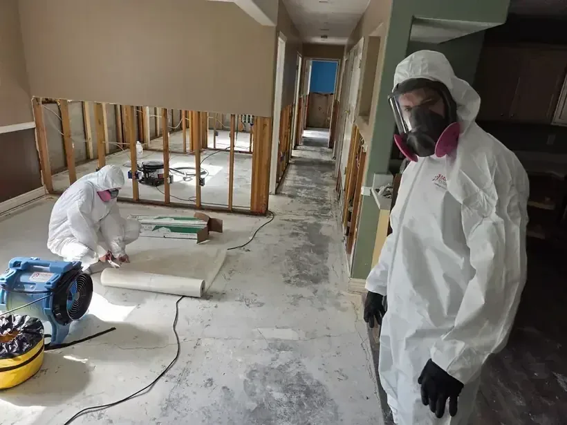 Technicians in protective suits cleaning a floor after a sewage backup