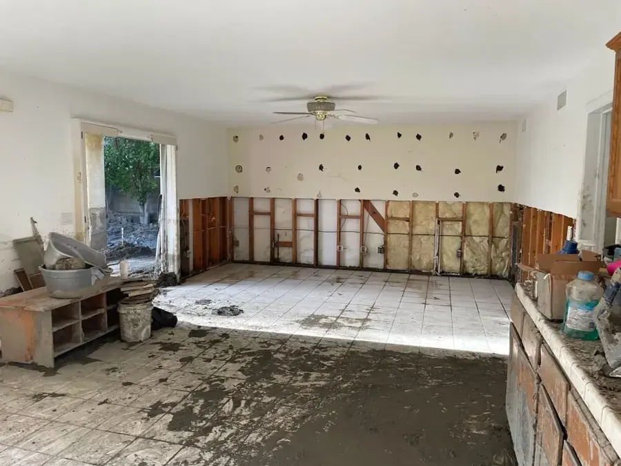 A room with the lower walls cut open and mud on the floor after flood water